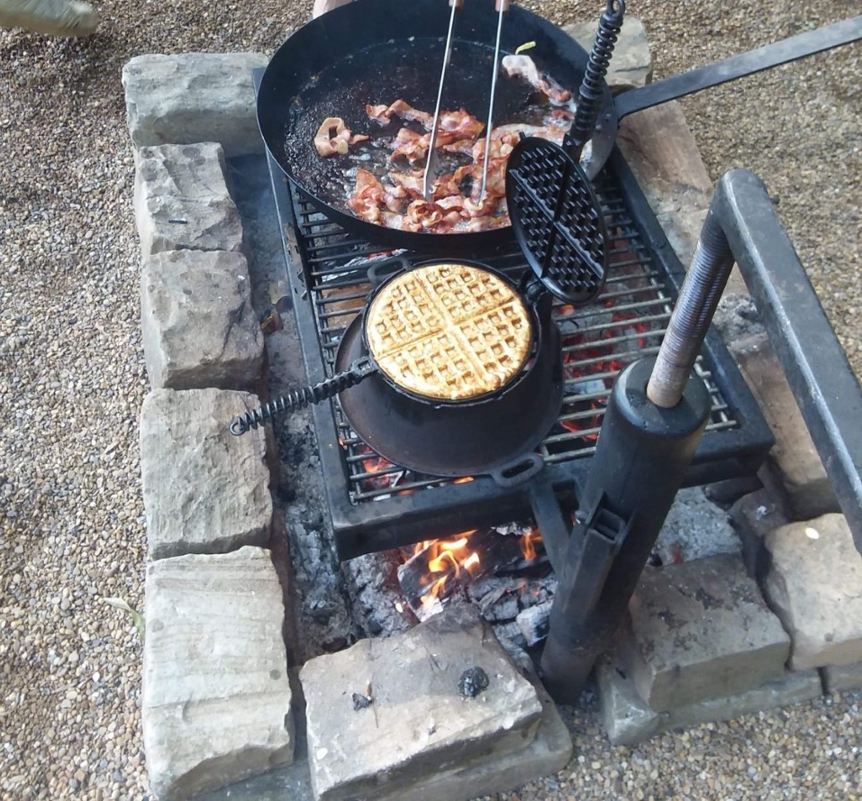 Cooking over campfire grill. Large skillet and waffle iron.